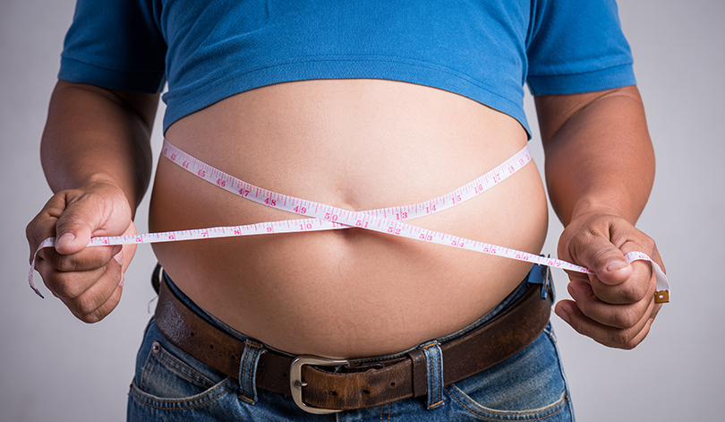 overweight or fat adult man in very tight jeans with measuring t